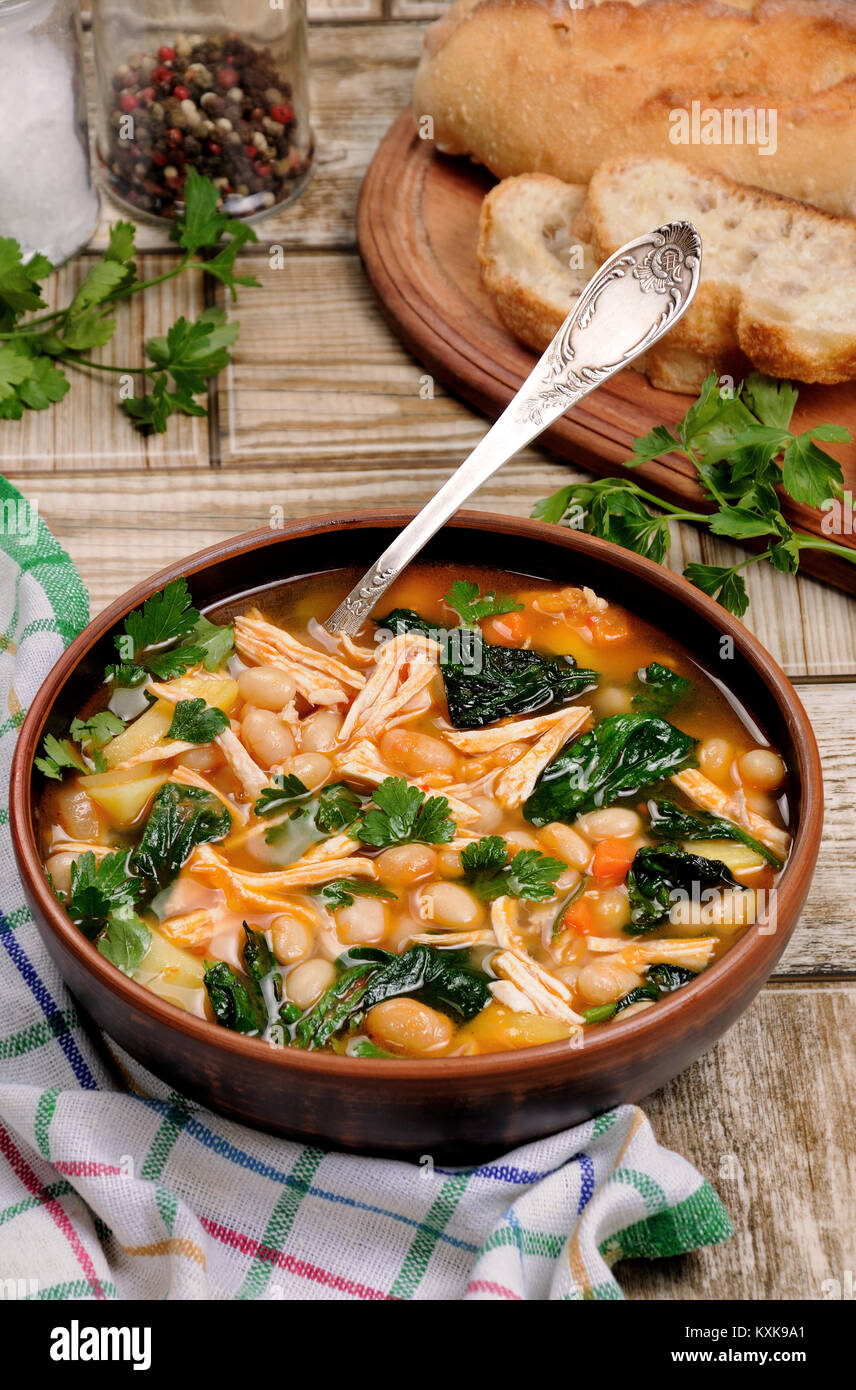 Sopa de pollo con judías blancas, las espinacas y el tomate Fotografía