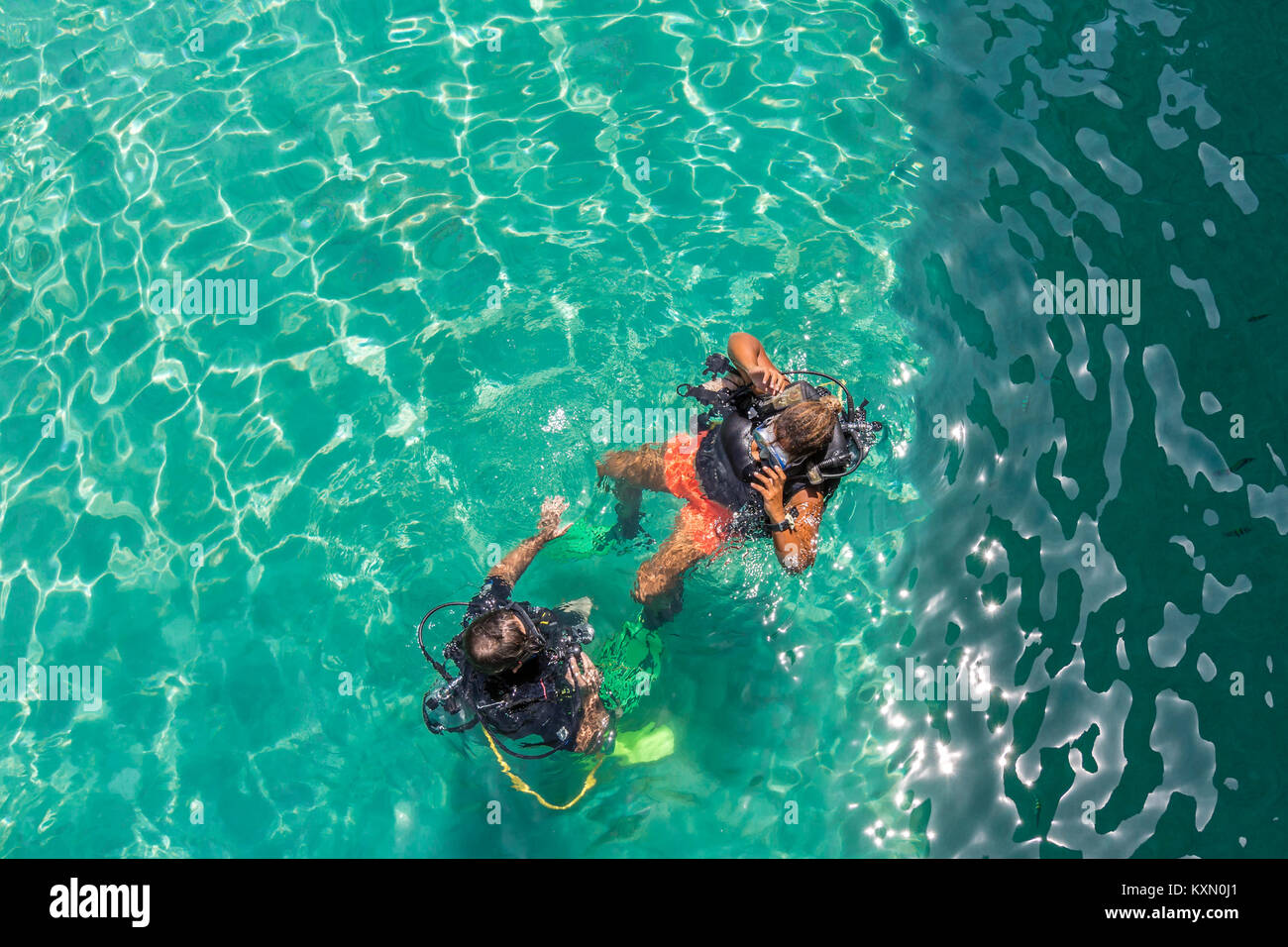Un grupo de alumnos de buceo tienen una lección en las poco profundas aguas cristalinas de una isla tropical. Foto de stock