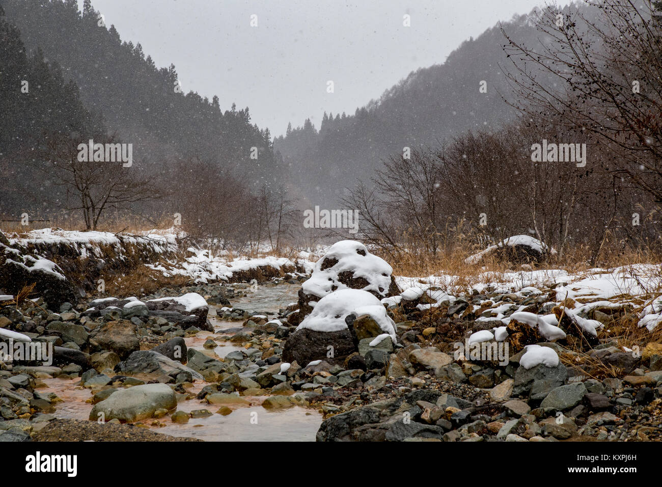 La Yokoku río fluye a través de las rocas. El río es alimentado por aguas termales en las montañas, por lo que permanece caliente incluso en el frío del invierno. Foto de stock