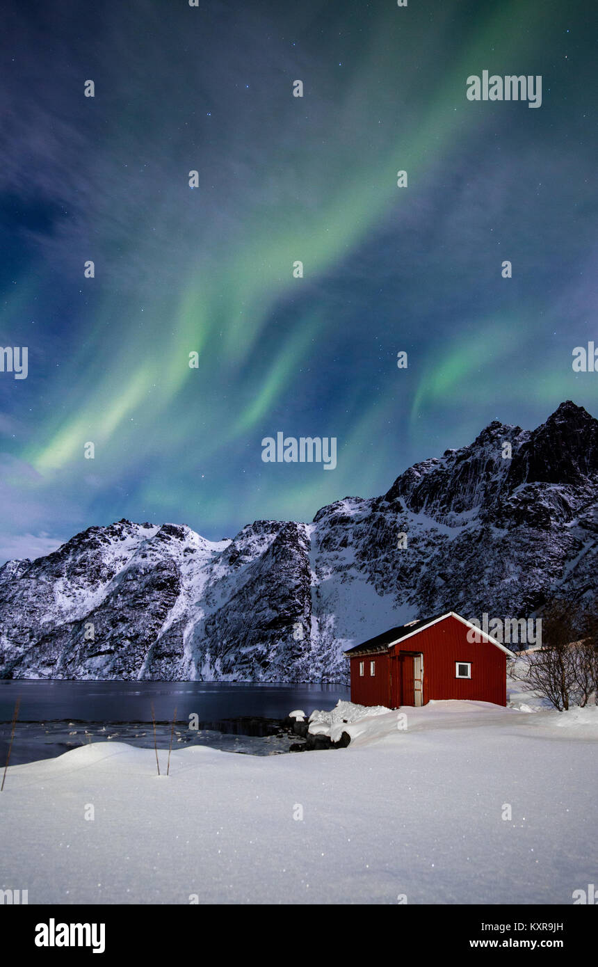 , Svolvaer Lofoten, Aurora Borealis sobre un lago congelado y rojo rorbu, Noruega. Foto de stock