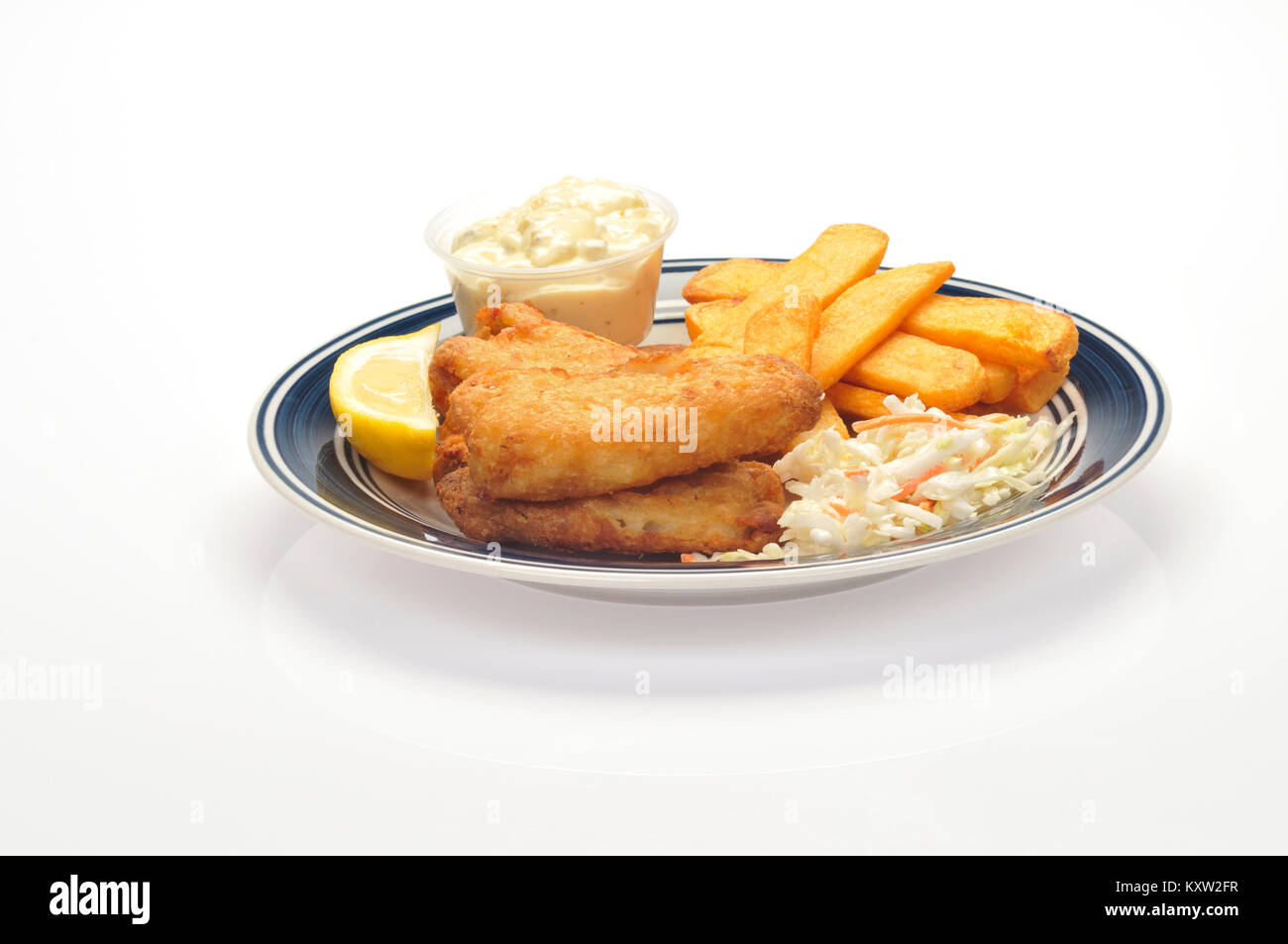 Pescado frito con patatas fritas y una cuña de limón, coleslaw y salsa tártara sobre placa azul y blanco sobre fondo blanco cortado Foto de stock