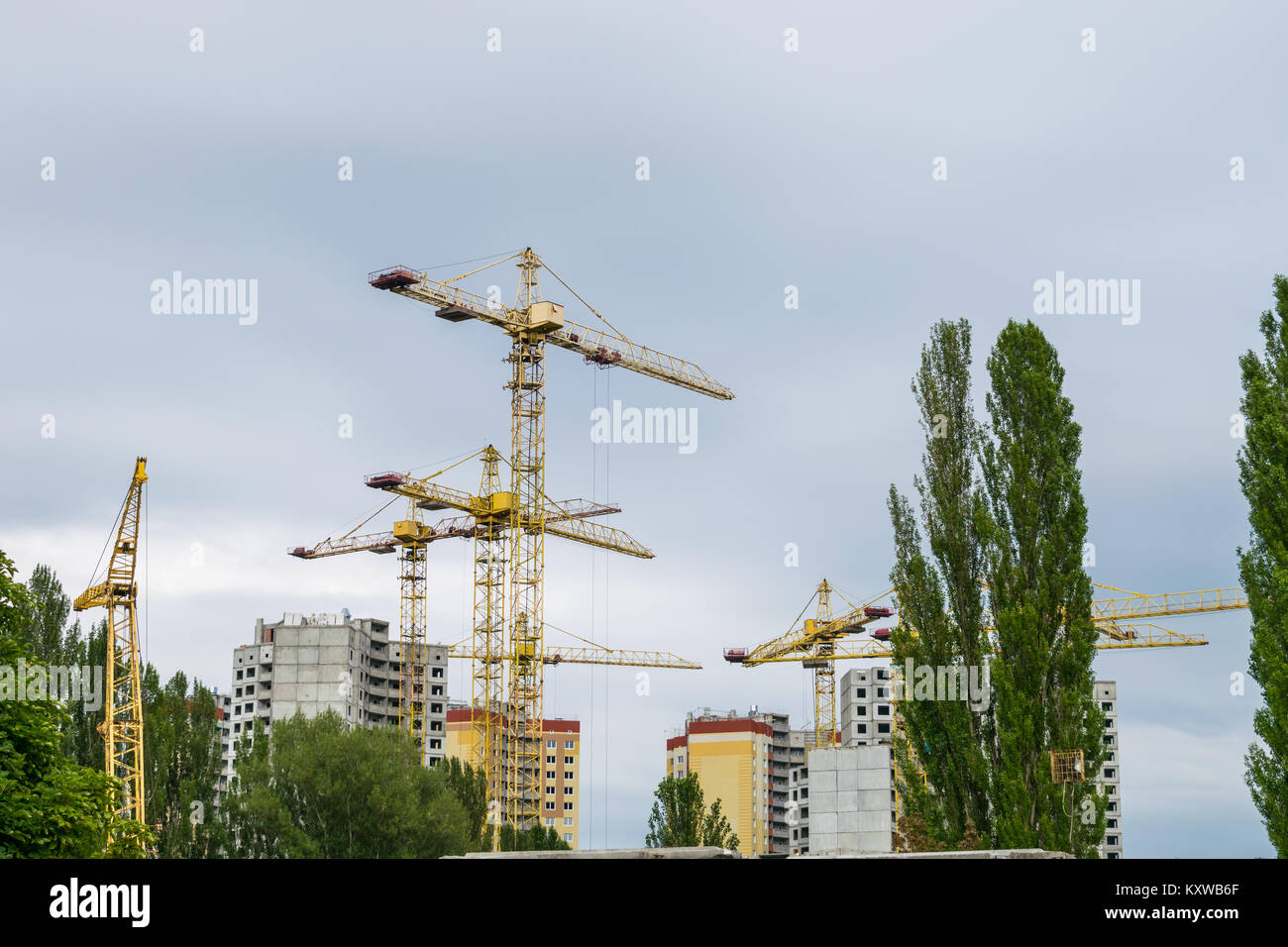 Varias grúas de construcción desarrollar los edificios en un día nublado Foto de stock