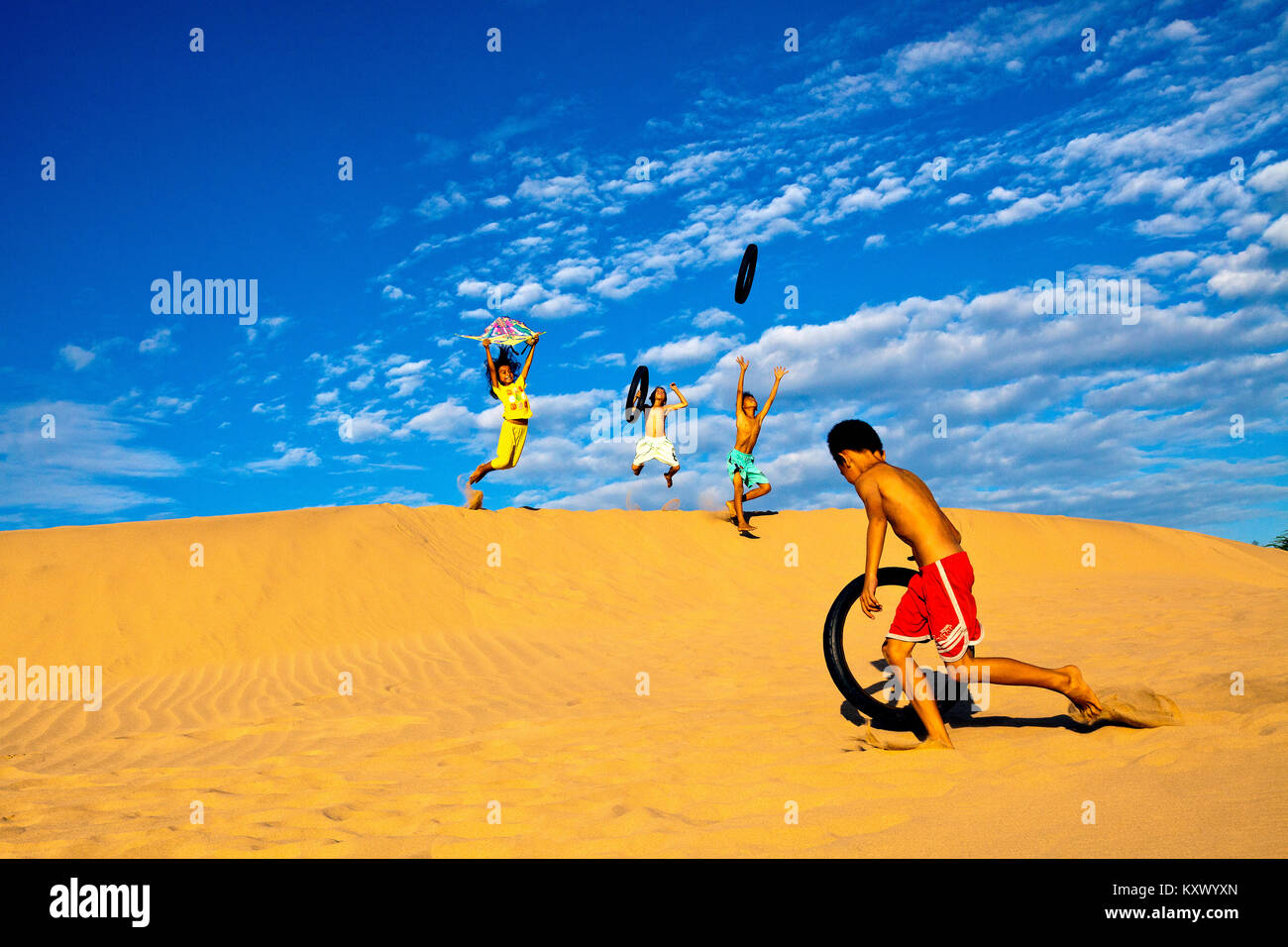 Niños jugando en las dunas de arena cerca de Phan Rang, Vietnam central Foto de stock