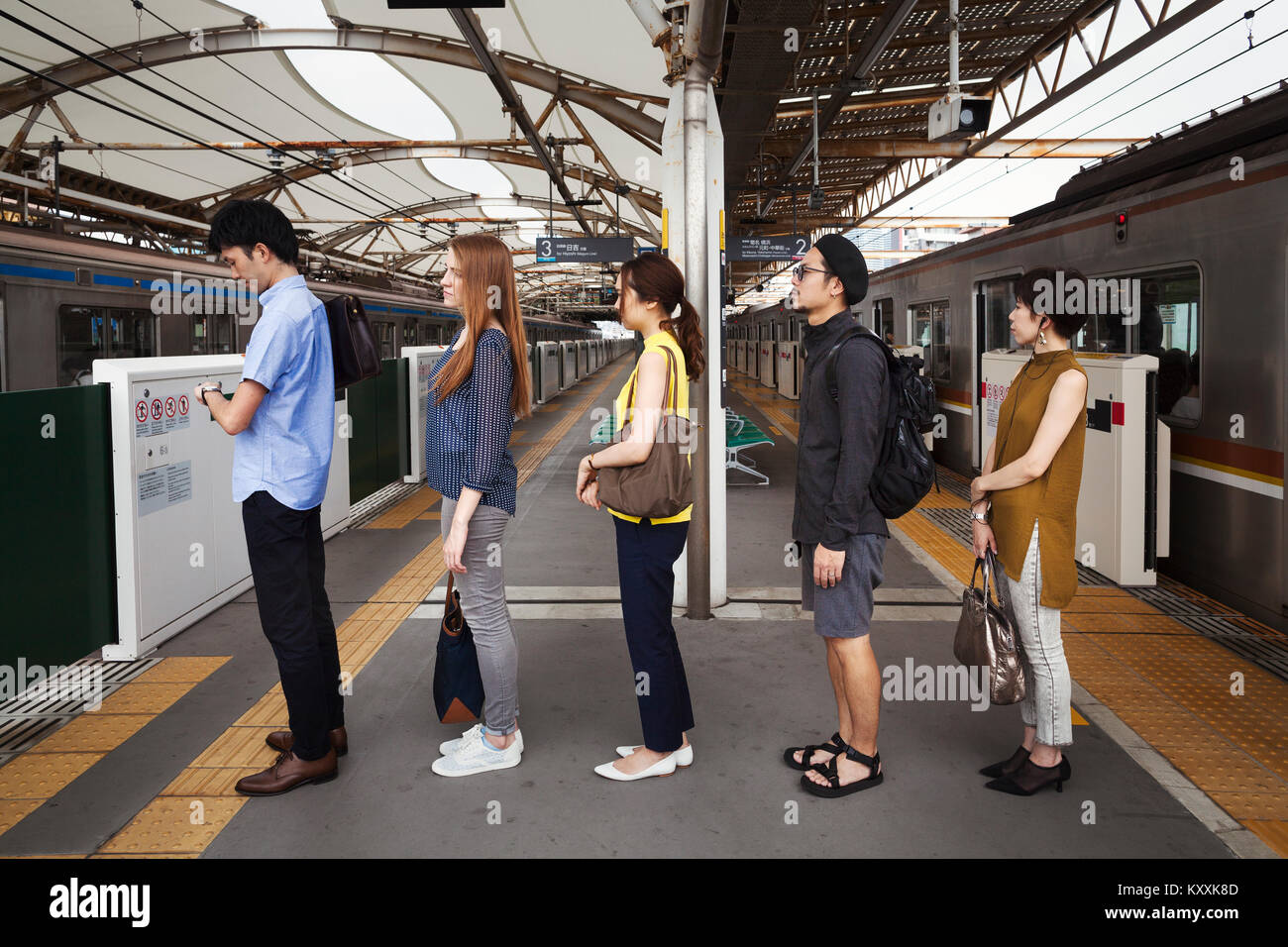 Cinco personas de pie en una fila en una plataforma del metro, esperando en  línea, viajeros de Tokio Fotografía de stock - Alamy