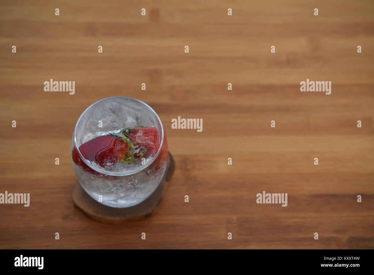 Comida y bebida cerca de la imagen de la fotografía de un vaso de hielo de agua burbujeante espumoso con fruta fresca fresa entera en madera espacio de fondo Foto de stock