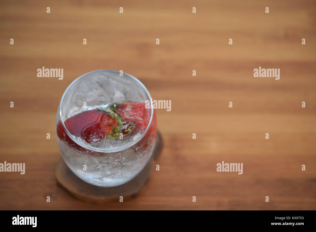 Comida y bebida cerca de la imagen de la fotografía de un vaso de hielo de agua burbujeante espumoso con fruta fresca fresa entera en madera espacio de fondo Foto de stock