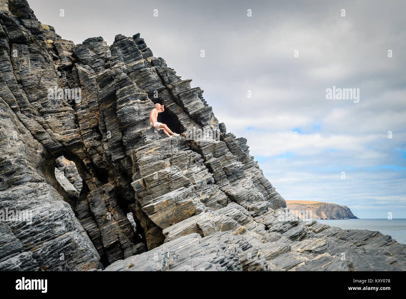 Hombre sentado en el acantilado y mirando en la distancia en Rapid Bay, Australia del Sur Foto de stock
