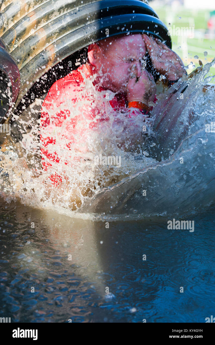 Sussex, Reino Unido. Un competidor tiene su nariz cerrada como él salpica en un gran charco de agua fría o hielo durante una dura Mudder evento. Foto de stock