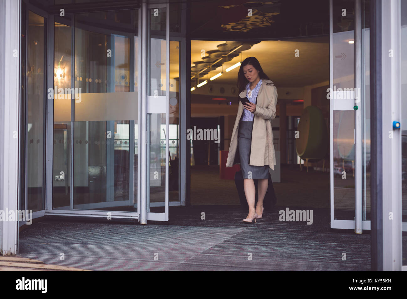La empresaria a través de teléfono móvil mientras camina fuera del hotel Foto de stock