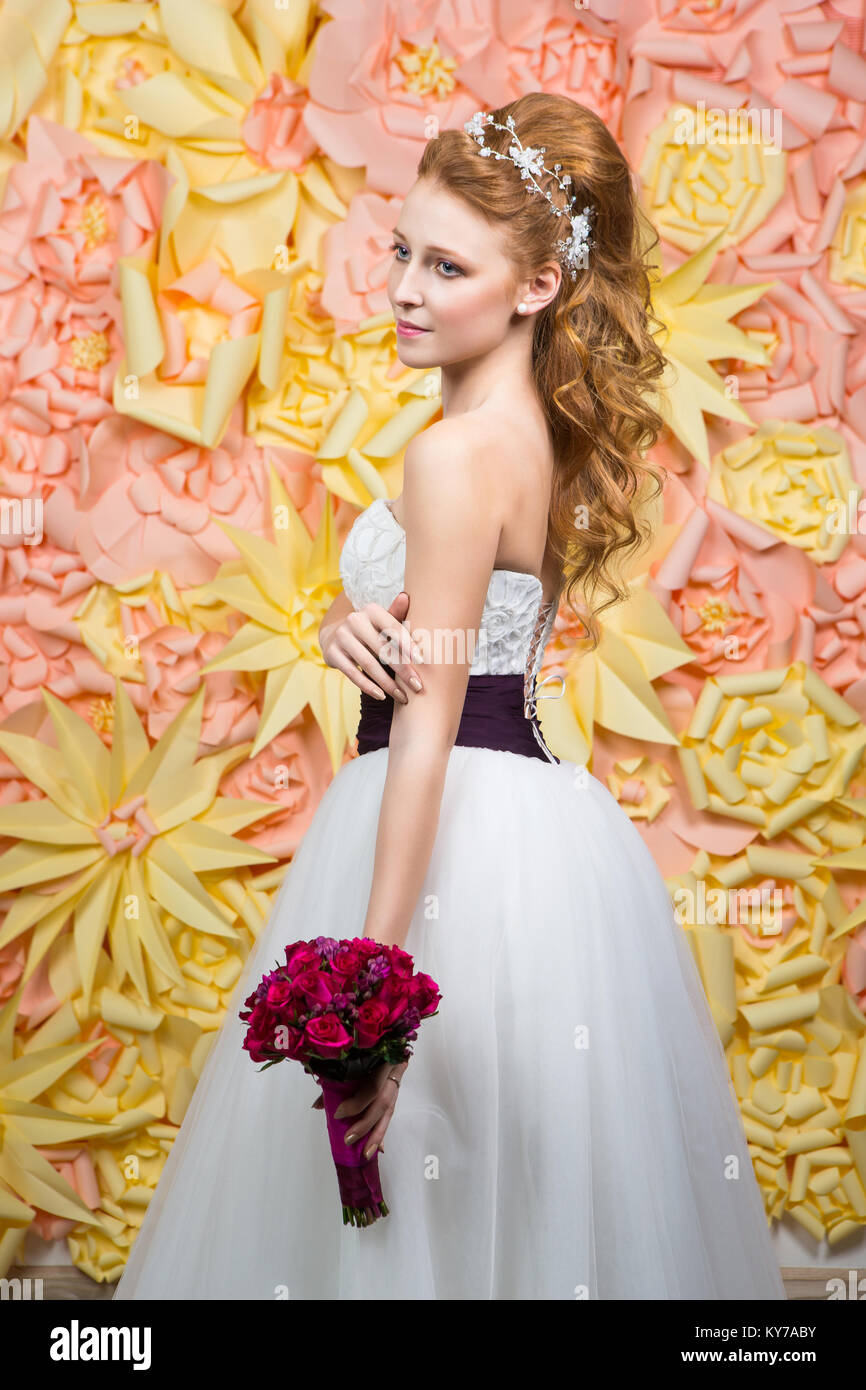 Hermoso cabello rojo joven en blanco vestido de novia con un amplio  cinturón de color púrpura oscuro. novia peinados de moda. Foto de estudio  Fotografía de stock - Alamy