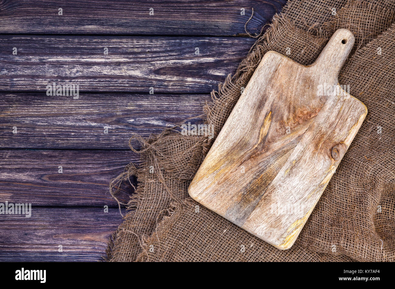 Mesa de madera con tela de arpillera y placa de corte Foto de stock