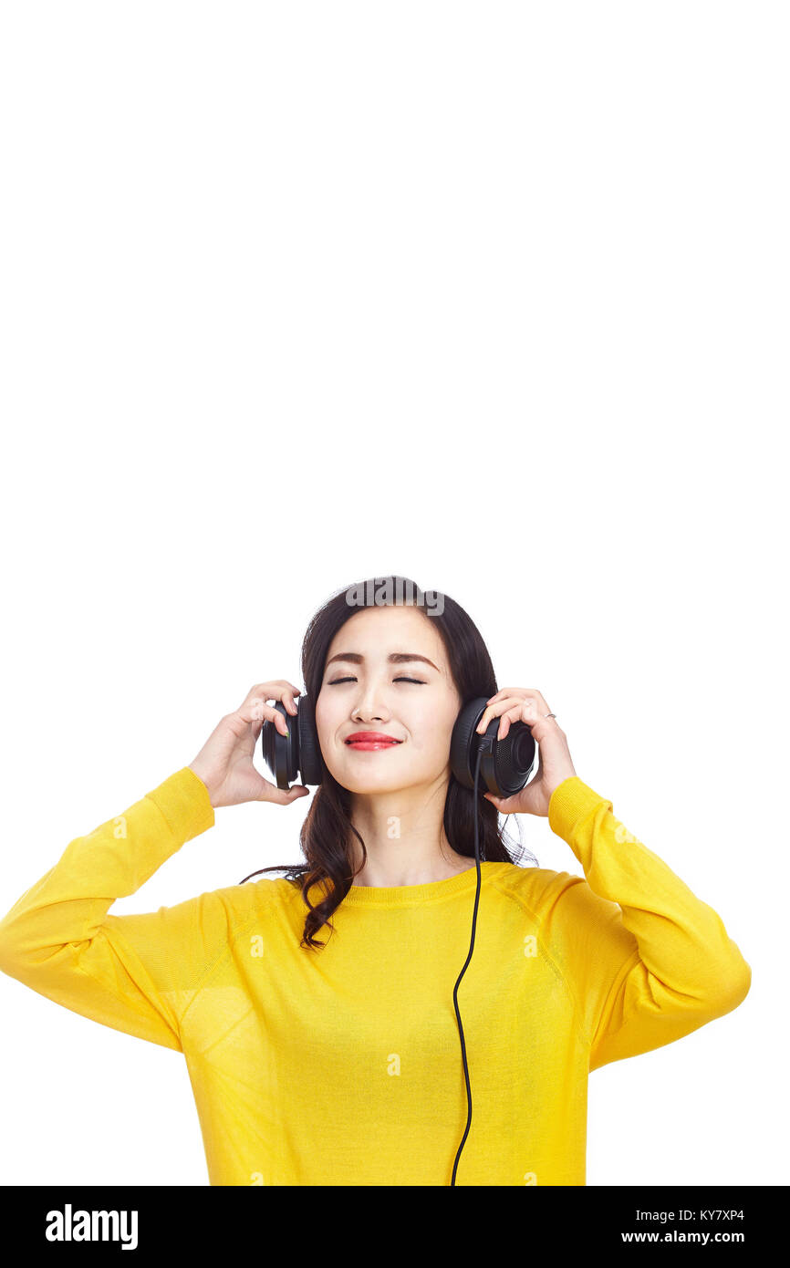 Foto de estudio de una joven y bella mujer asiática escuchar y disfrutar de la música con los auriculares, los ojos cerrados, aislado sobre fondo blanco. Foto de stock