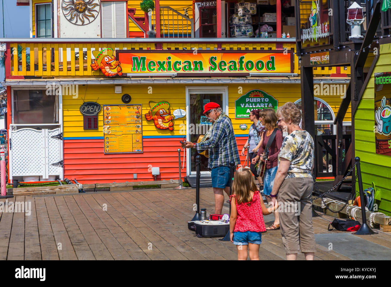 Músicos en Fisherman's Wharf en Victoria, Canadá, una atracción turística con quioscos de comida, tiendas y hogares de flotación o houseboats Foto de stock