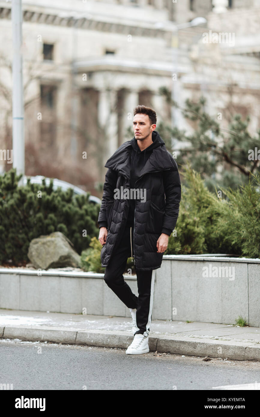 Hombre elegante wolk en la calle. El frío del invierno outfit. Gran  chaqueta con zapatillas blancas. Antecedentes Blured street. Foto modelo  profecional Fotografía de stock - Alamy