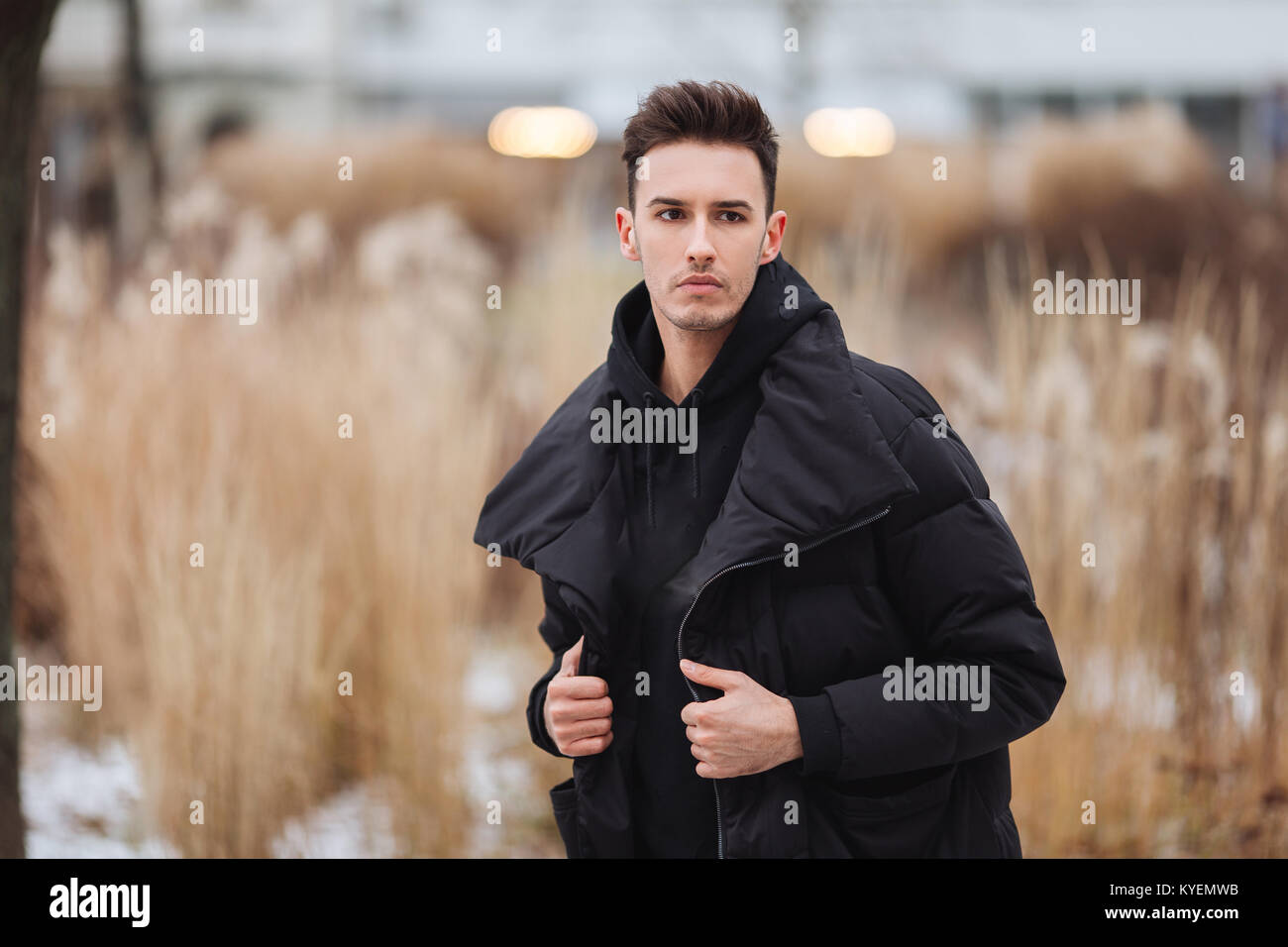 Hombre elegante wolk en la calle. El frío del invierno outfit. Gran  chaqueta con zapatillas blancas. Antecedentes Blured street. Foto modelo  profecional Fotografía de stock - Alamy