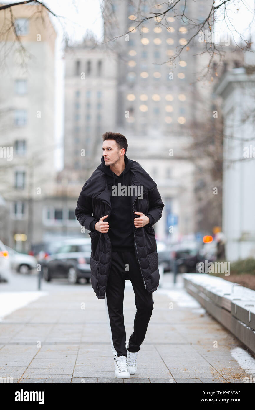 Hombre elegante wolk en la calle. El frío del invierno outfit. Gran  chaqueta con zapatillas blancas. Antecedentes Blured street. Foto modelo  profecional Fotografía de stock - Alamy