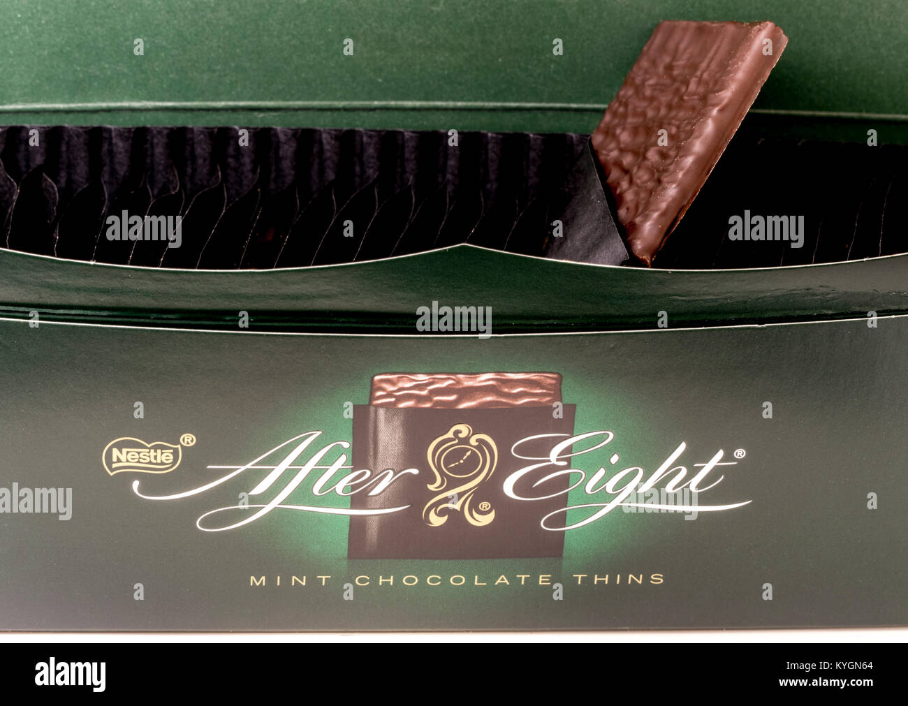 Nestlé tras ocho chocolates (después de ochos). Primer plano de una caja abierta y logotipo, con una forma cuadrada de menta chocolate oscuro delgada que sobresale de su envoltura. Foto de stock