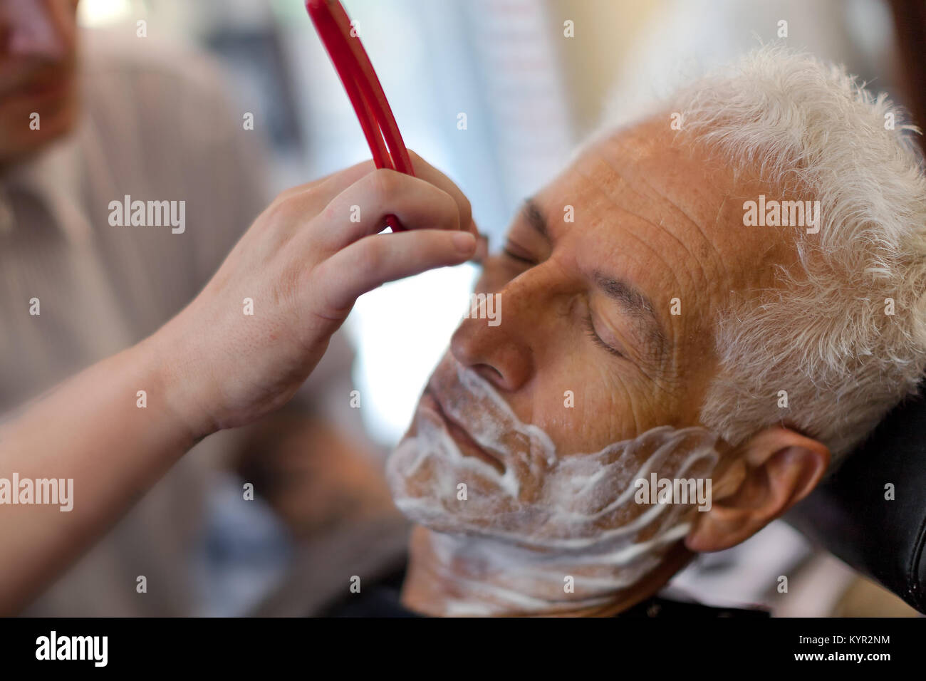 Viejo obteniendo un afeitado con un borde recto razor en una peluquería. Cerrar Foto de stock