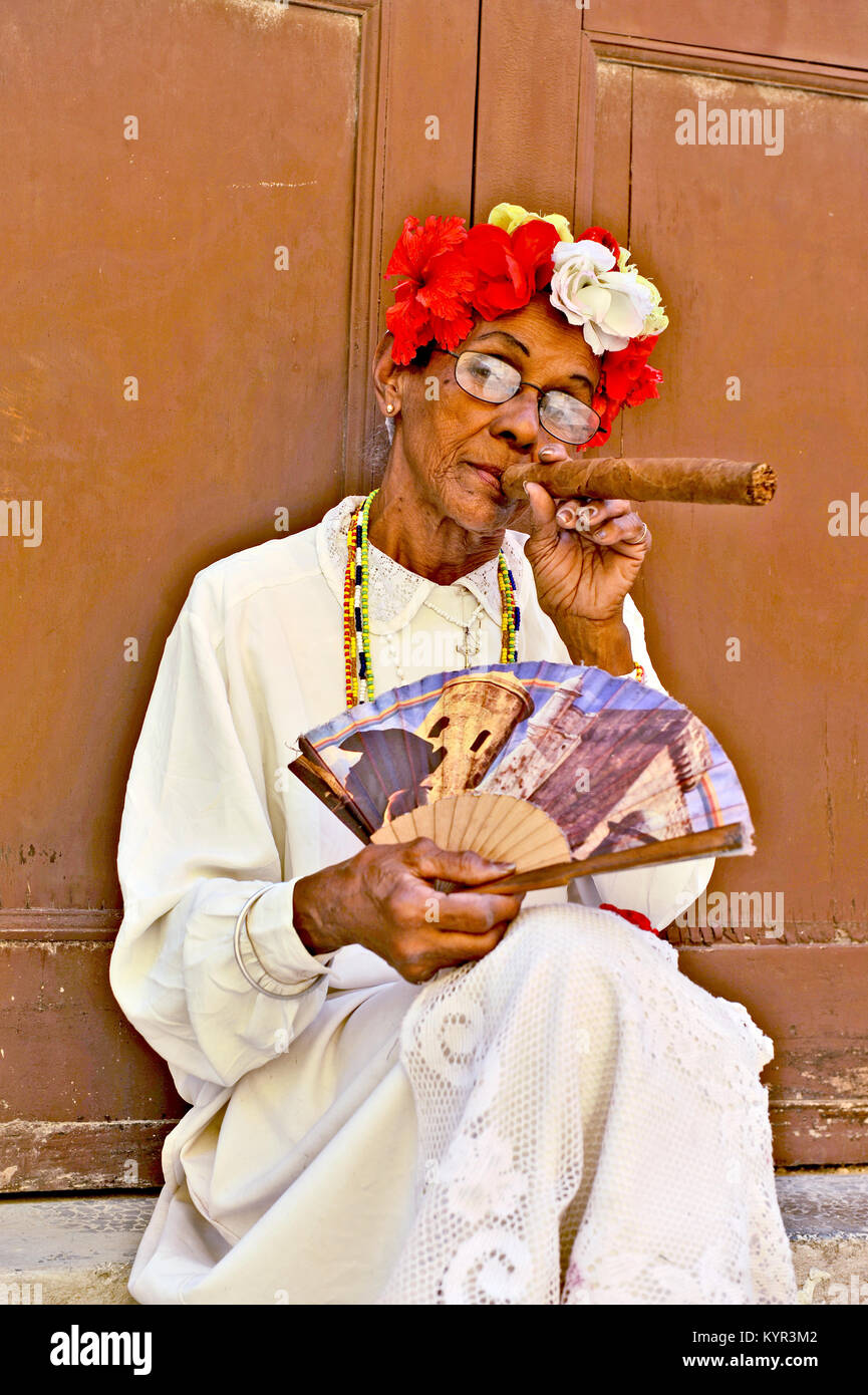 La Habana, Cuba, 6 de mayo de 2009. Una vieja mujer sentada con un enorme puro en la boca y rosas en su cabeza en La Habana, Cuba, el 7 de mayo de 2009. Foto de stock