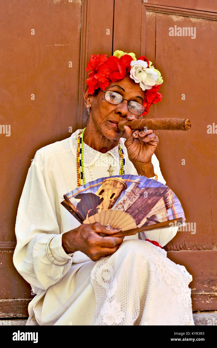 La Habana, Cuba, 6 de mayo de 2009. Una vieja mujer sentada con un enorme puro en la boca y rosas en su cabeza en La Habana, Cuba, el 7 de mayo de 2009. Foto de stock