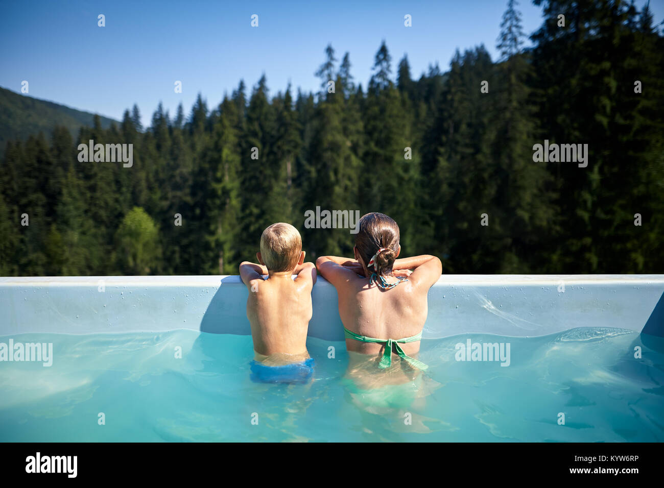 Los niños en la piscina mirando vistas pintorescas. Hermano y hermana, relájese en la piscina al aire libre durante los fines de semana. Retrato de familia de vacaciones y descanso, b Foto de stock