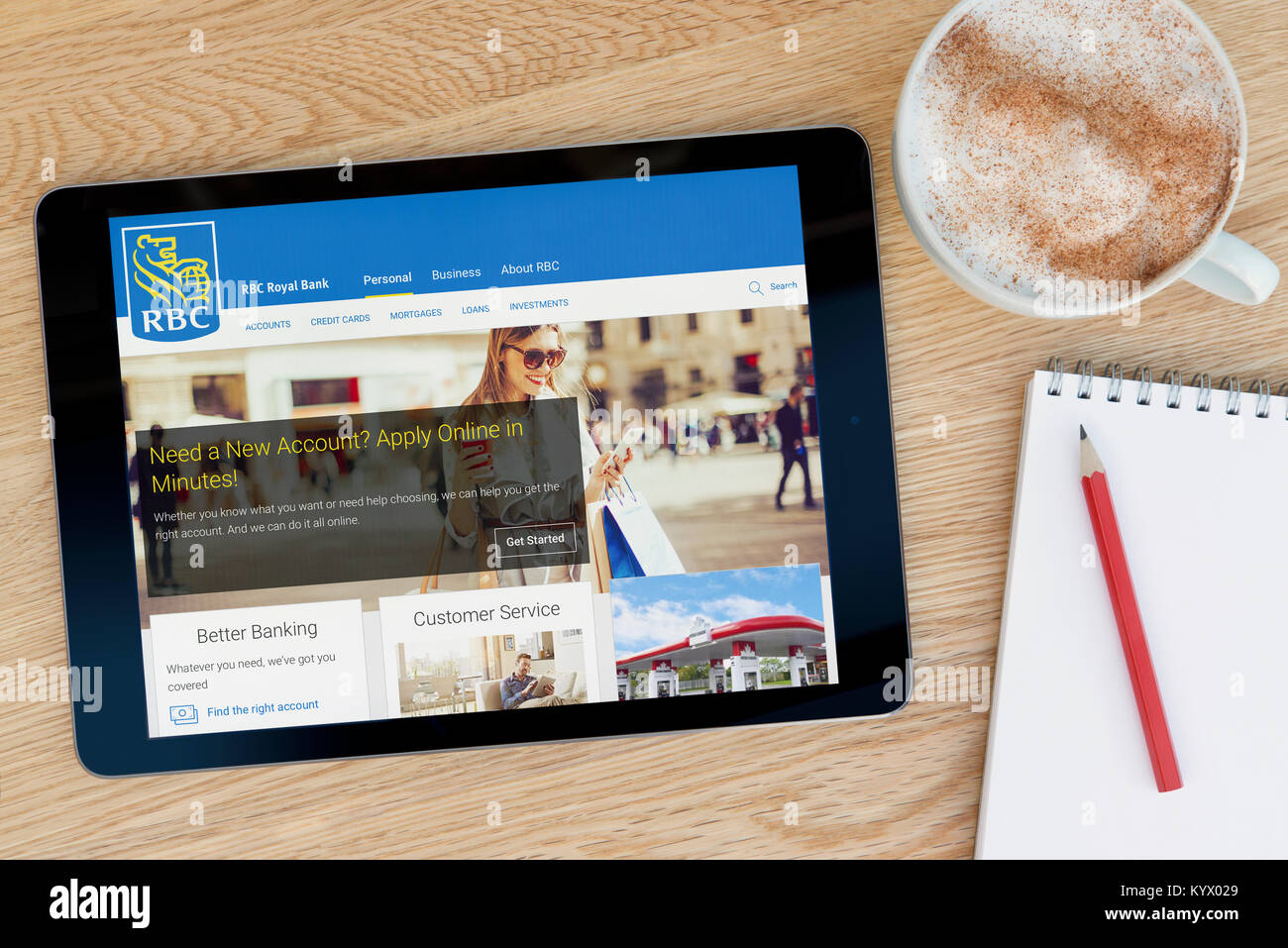 El sitio web del Royal Bank of Canada en un iPad, en una mesa de madera junto a un bloc de notas, lápiz y la taza de café (Editorial) Foto de stock