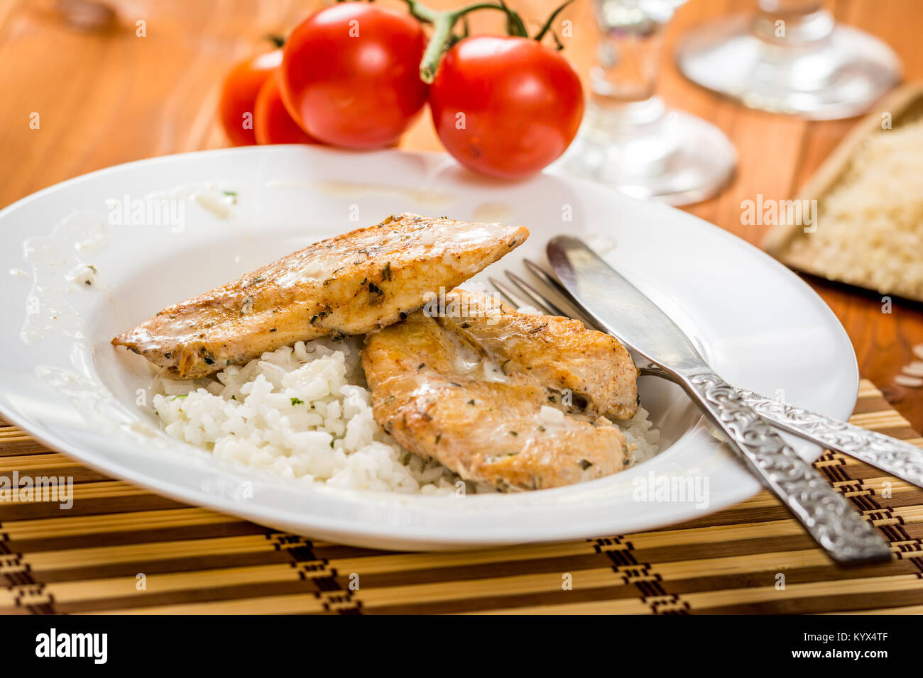 Pollo asado con salsa de albahaca y arroz en la placa blanca. Foto de stock