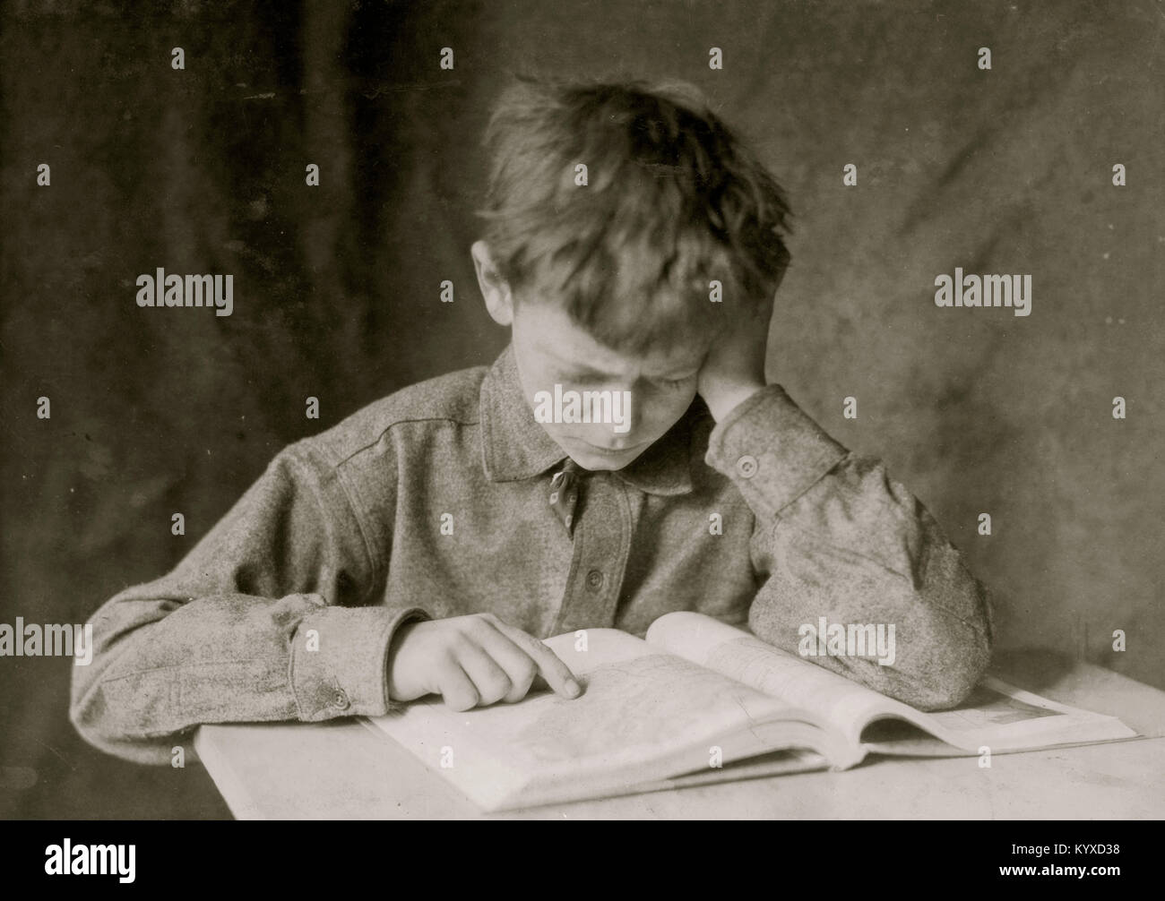 Un niño lee un libro y estudios Foto de stock