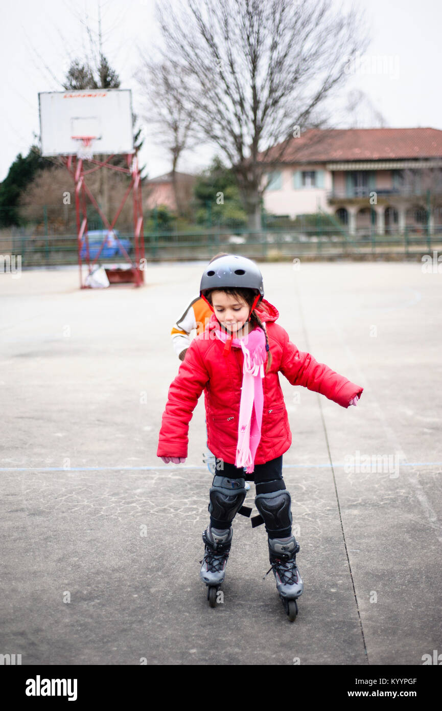 Niña aprende a patinar con patines en la cancha de básquetbol en un día de  invierno Fotografía de stock - Alamy