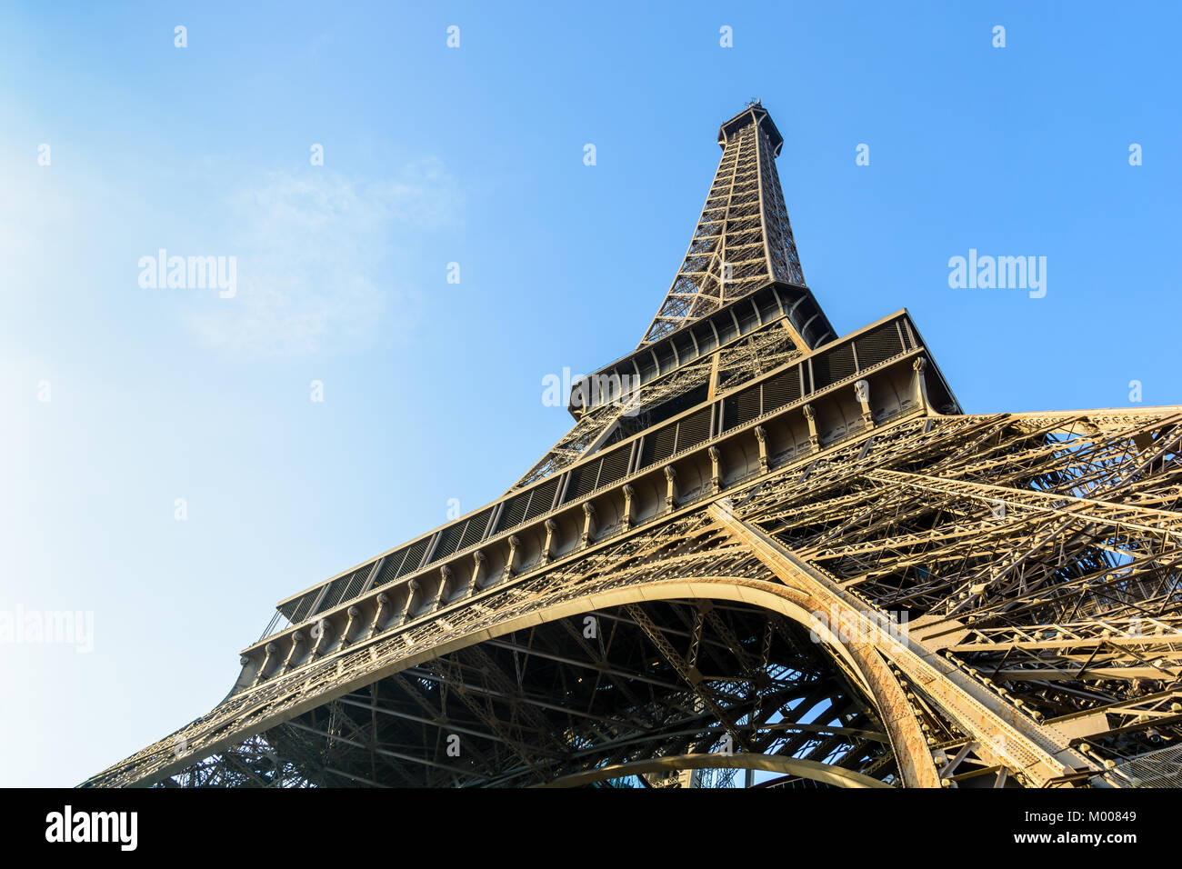 Vista dinámica desde debajo de la Torre Eiffel contra el cielo azul. Foto de stock