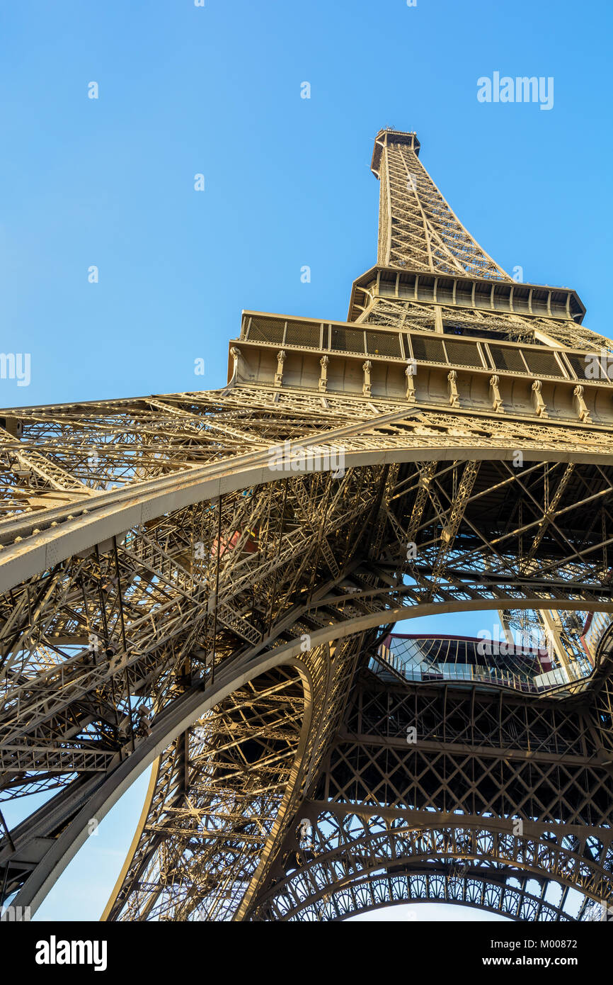 Vista dinámica desde debajo de la Torre Eiffel contra el cielo azul. Foto de stock