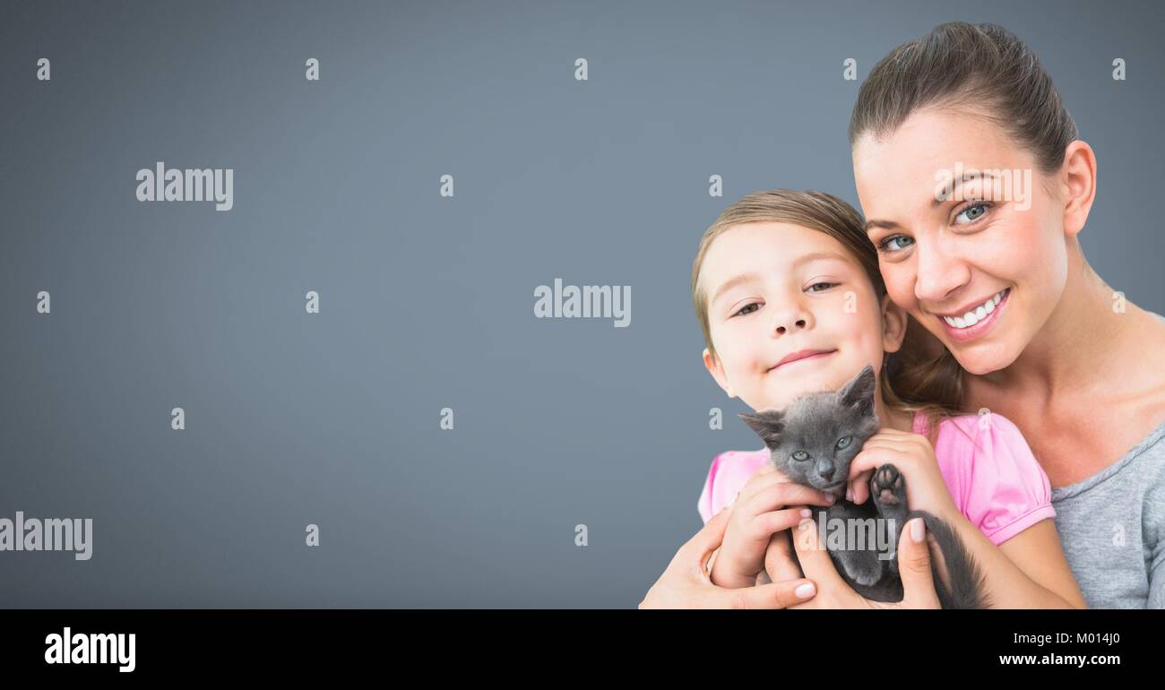 Madre e hija la celebración de gato con fondo gris Foto de stock