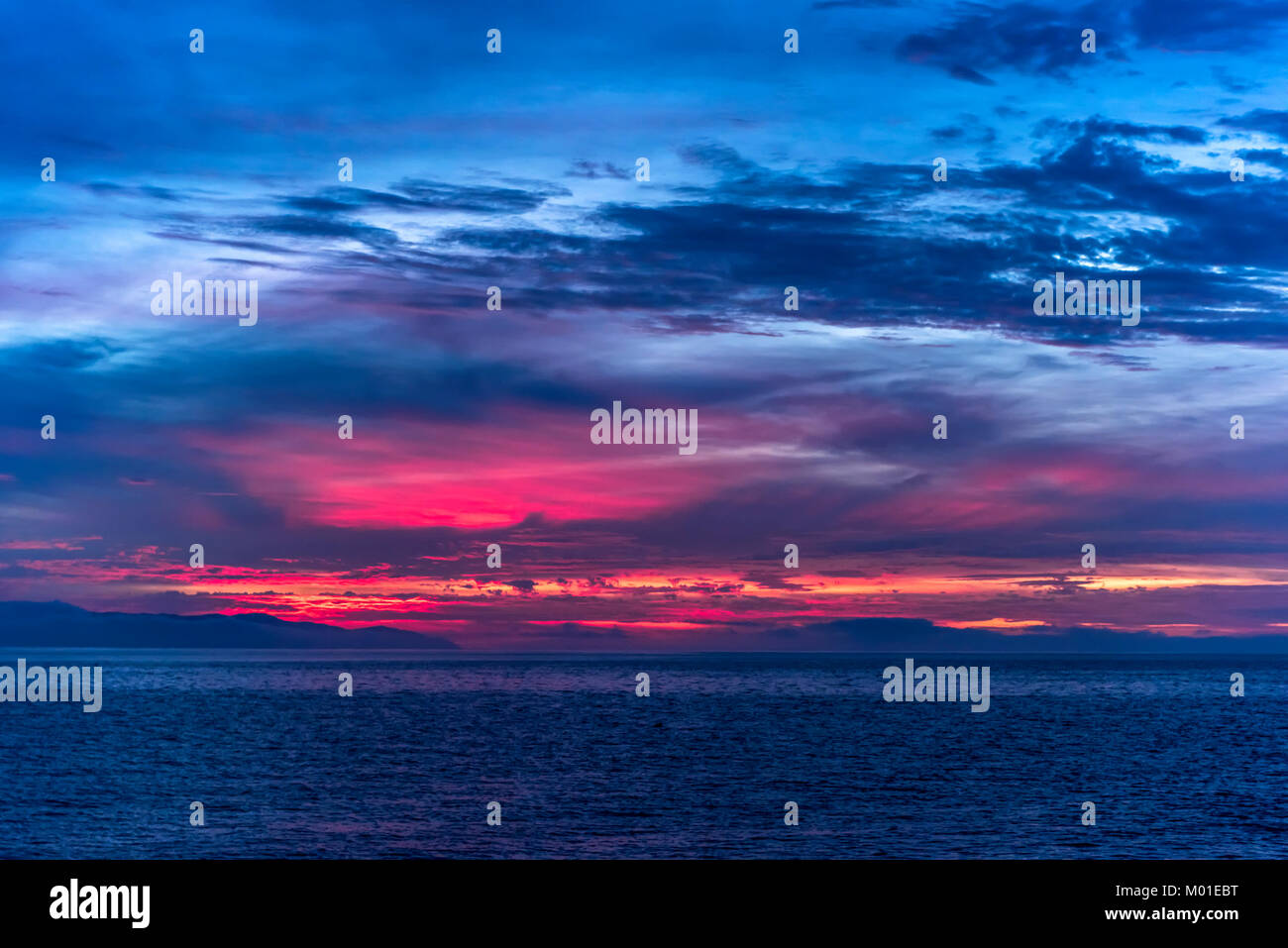 Un hermoso amanecer en las remotas islas del Canal de California muestra la vibrante y moody brillantemente iluminada por el sol rojo y naranja de las nubes. Foto de stock