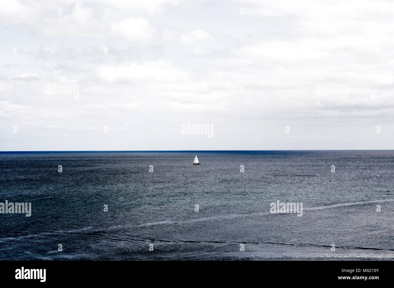Bote de vela en el mar bajo el cielo nublado en la costa de Mevagissey, Cornwall Foto de stock