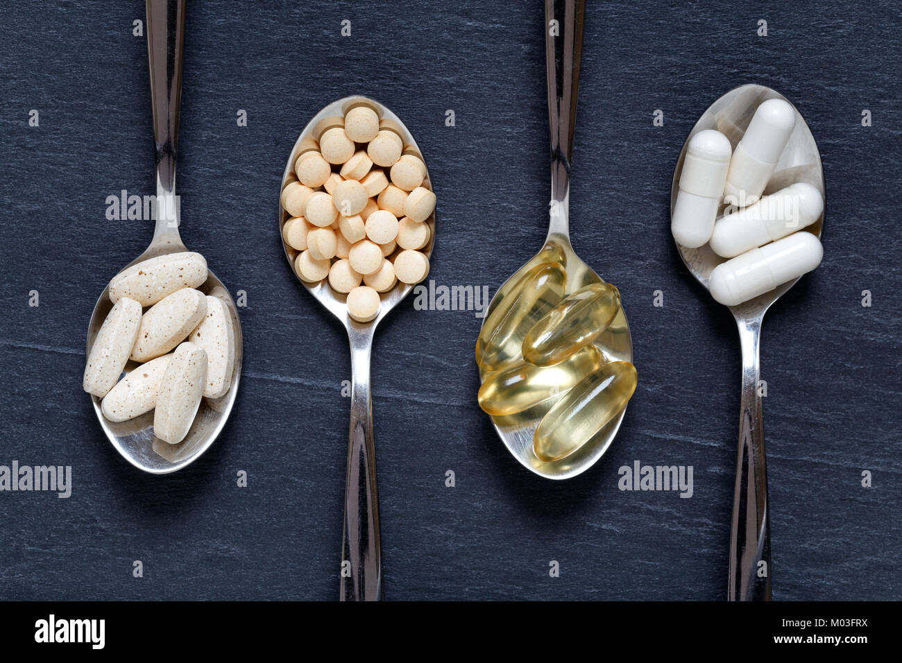 Healty vitaminas, minerales, omega 3 y antioxidantes en cucharaditas contra un fondo oscuro Foto de stock