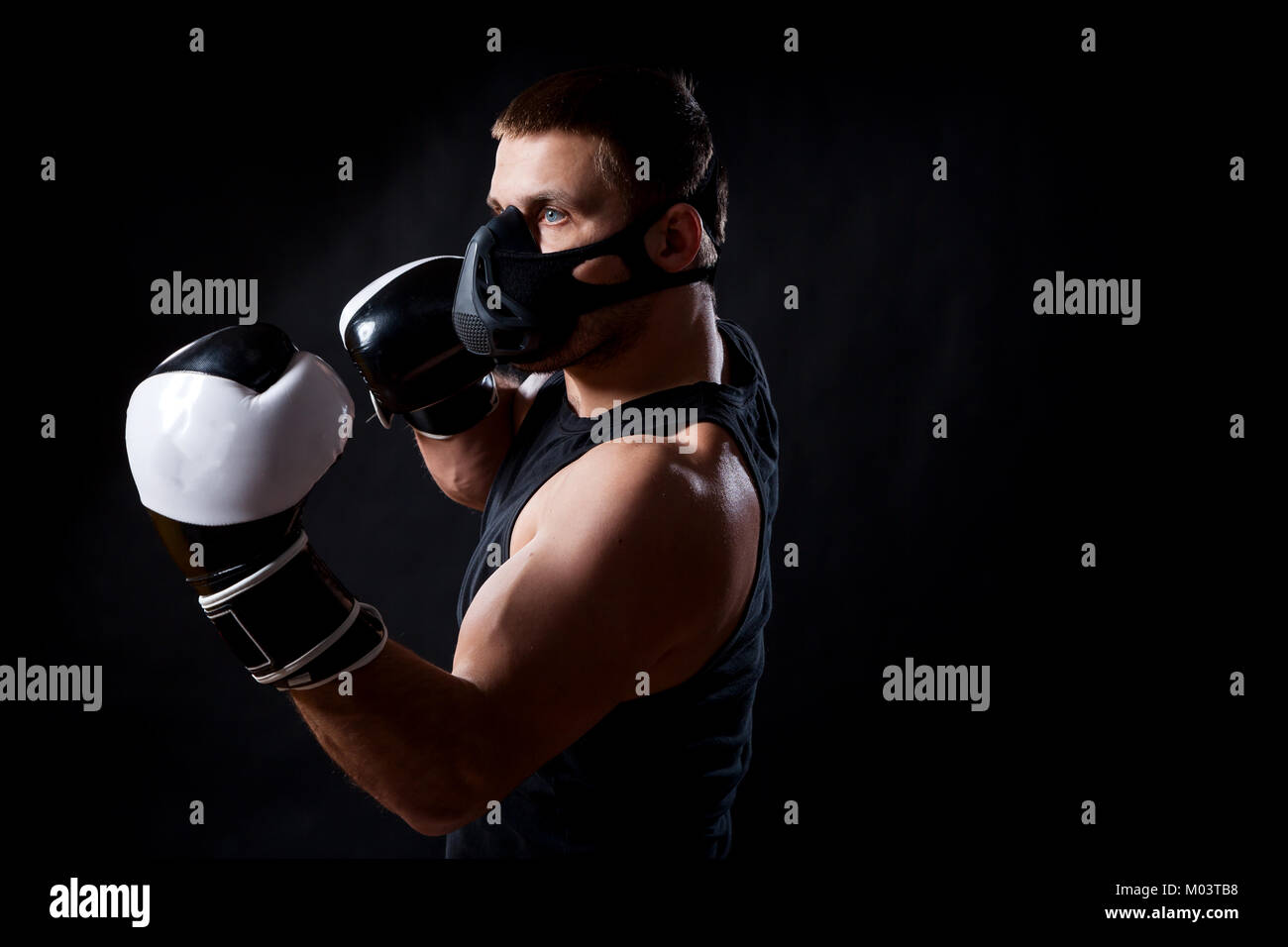 Una morena atleta masculino en una máscara negra, camiseta de entrenamiento  deportivo y blanco y negro Guantes boxeo boxeo negro sobre un fondo aislado  Fotografía de stock - Alamy