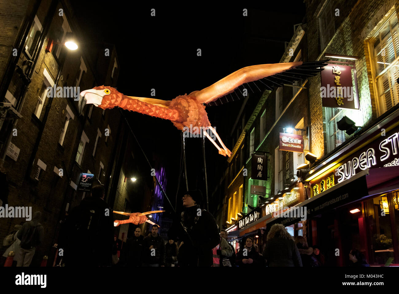 Londres, Reino Unido. El 18 de enero de 2018. Lumiere Londres vuelve el festival de la luz por segunda vez. Más de cincuenta obras transformar las calles de la capital en una deslumbrante exhibición de arte libre nocturno. Más de un millón de visitantes asistieron a los cuatro días del primer Lumiere el festival de Londres en 2016. Lumiere Londres durará hasta el 21 de enero de 2018. Foto: Flamingo ruta migratoria, extraordinario color de llama aves creado por la siempre imaginativa Empresa Linterna con Jo Pocock (Reino Unido), a medida que desfilan serenamente en Chinatown de Londres. La pieza hace referencia a la extraordinaria intercontinental que las rutas de migración de aves. Foto de stock