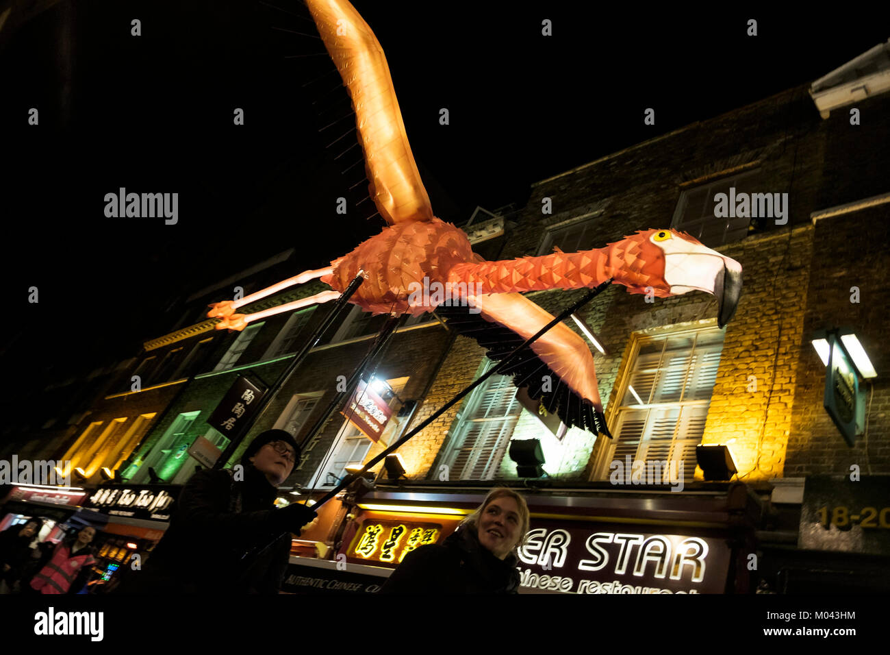 Londres, Reino Unido. El 18 de enero de 2018. Lumiere Londres vuelve el festival de la luz por segunda vez. Más de cincuenta obras transformar las calles de la capital en una deslumbrante exhibición de arte libre nocturno. Más de un millón de visitantes asistieron a los cuatro días del primer Lumiere el festival de Londres en 2016. Lumiere Londres durará hasta el 21 de enero de 2018. Foto: Flamingo ruta migratoria, extraordinario color de llama aves creado por la siempre imaginativa Empresa Linterna con Jo Pocock (Reino Unido), a medida que desfilan serenamente en Chinatown de Londres. La pieza hace referencia a la extraordinaria intercontinental que las rutas de migración de aves. Foto de stock