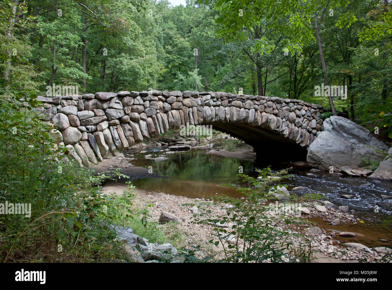 Puente de Piedra sobre un arroyo en DC Park Foto de stock