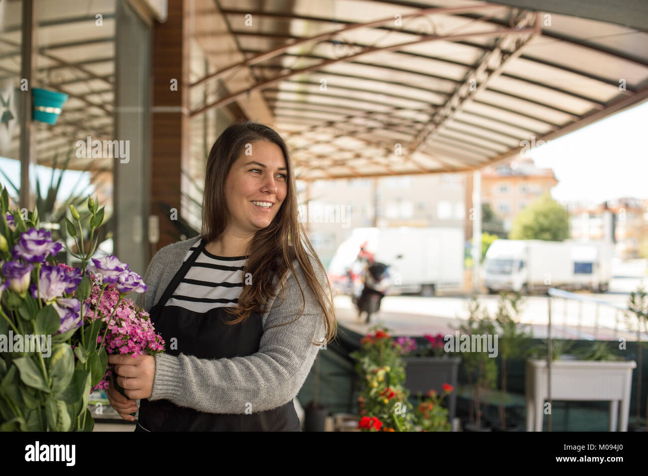 Concepto de negocio pequeño. Hembra Smilng floristería recogiendo flores en una tienda de flores. Foto de stock