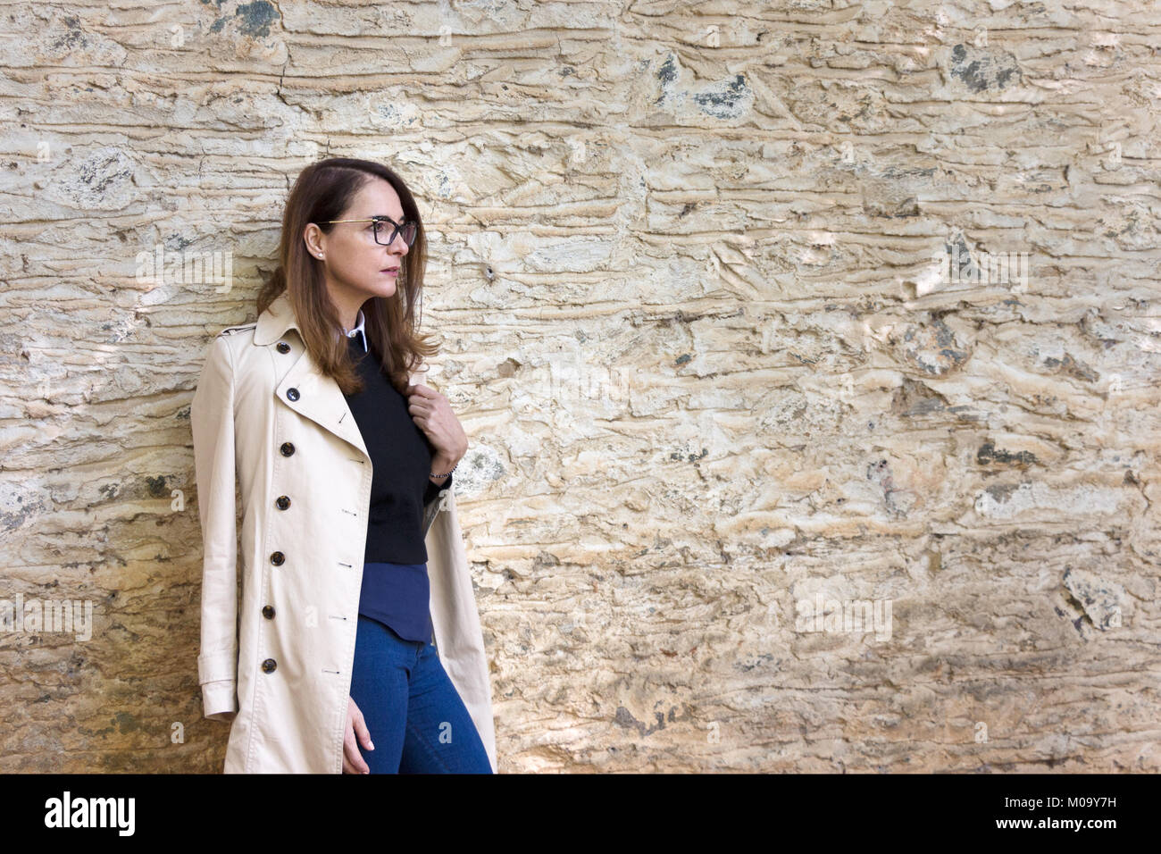 Una mujer madura delgada llevar anteojos retro, 46 años, de pie, vista de perfil, mirando a otro lado. Foto de stock