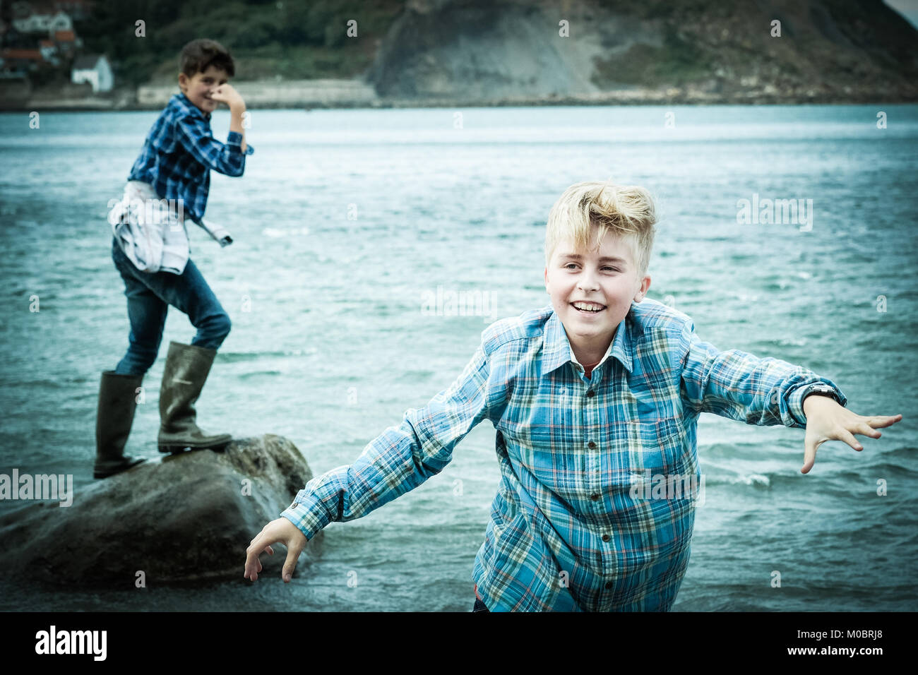 Dos hermanos, los niños de 12 y 10 años, en el mar, almejas, jugando en Runswick Bay, Yorkshire, Reino Unido Foto de stock
