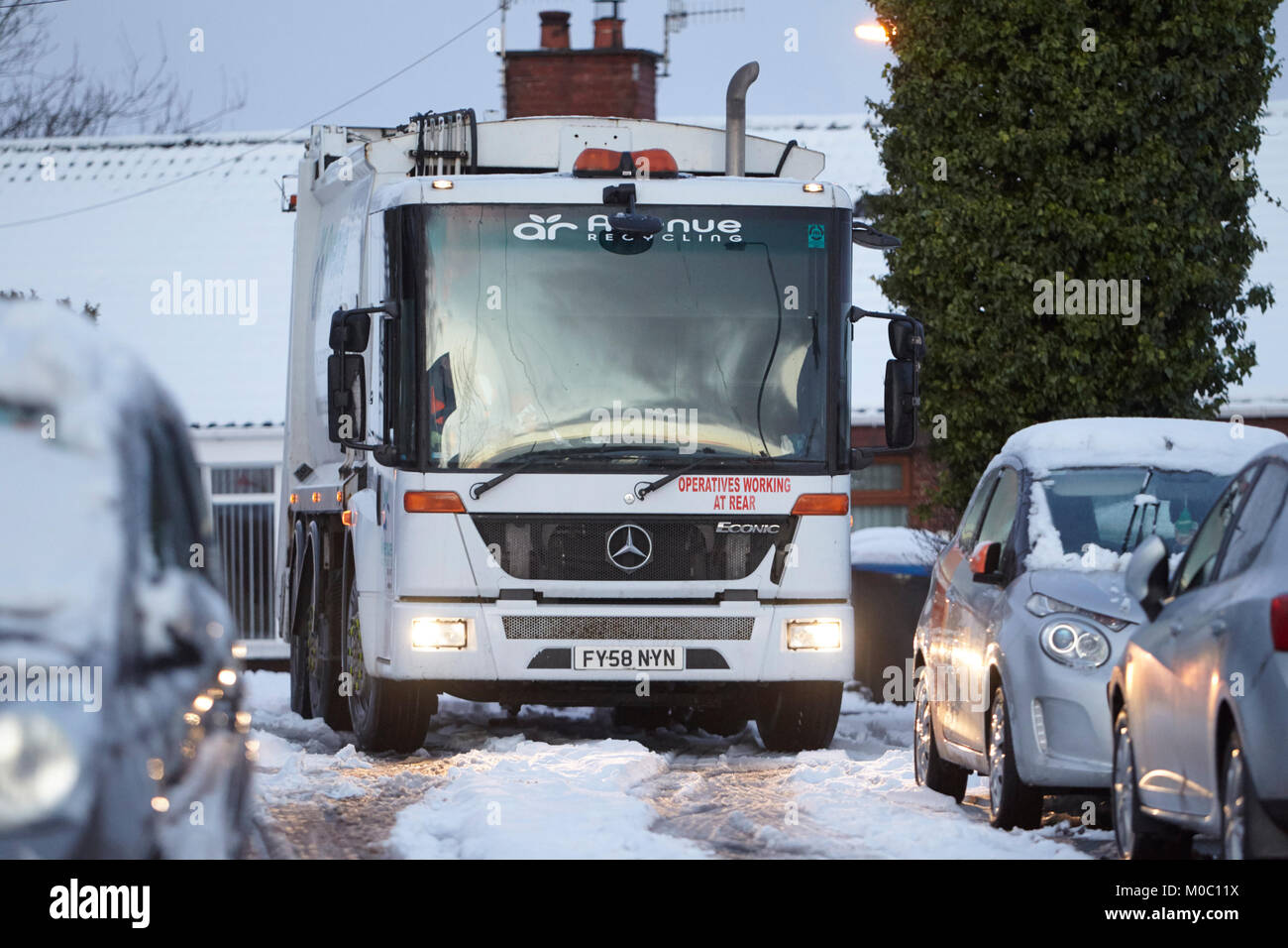 Mercedes econic rechazar colección de reciclaje la conducción de camiones a lo largo de calle cubierta de nieve en Newtownabbey Irlanda del Norte Foto de stock