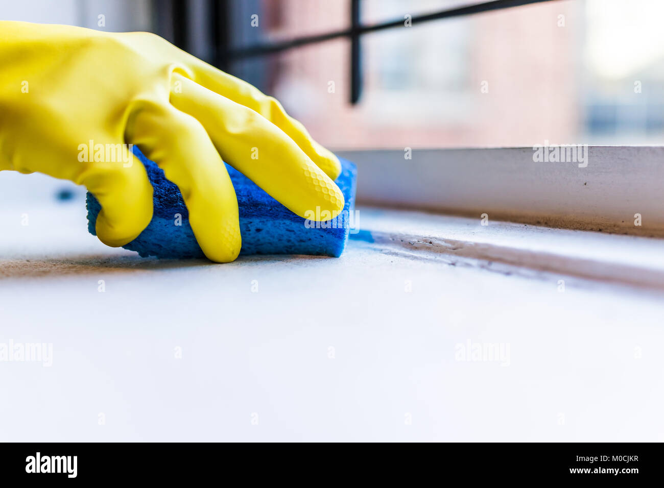 Limpieza de manos guantes amarillos suciedad en el alféizar con azul por la ventana en apartamento urbano en la Ciudad de York NUEVA YORK Fotografía de stock -