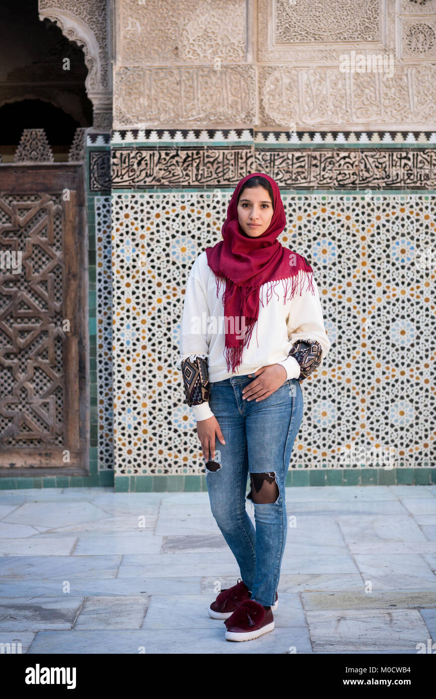 Mujer en ropa moderna con pañuelo rojo delante de la pared con el texto del Corán Fotografía de stock - Alamy