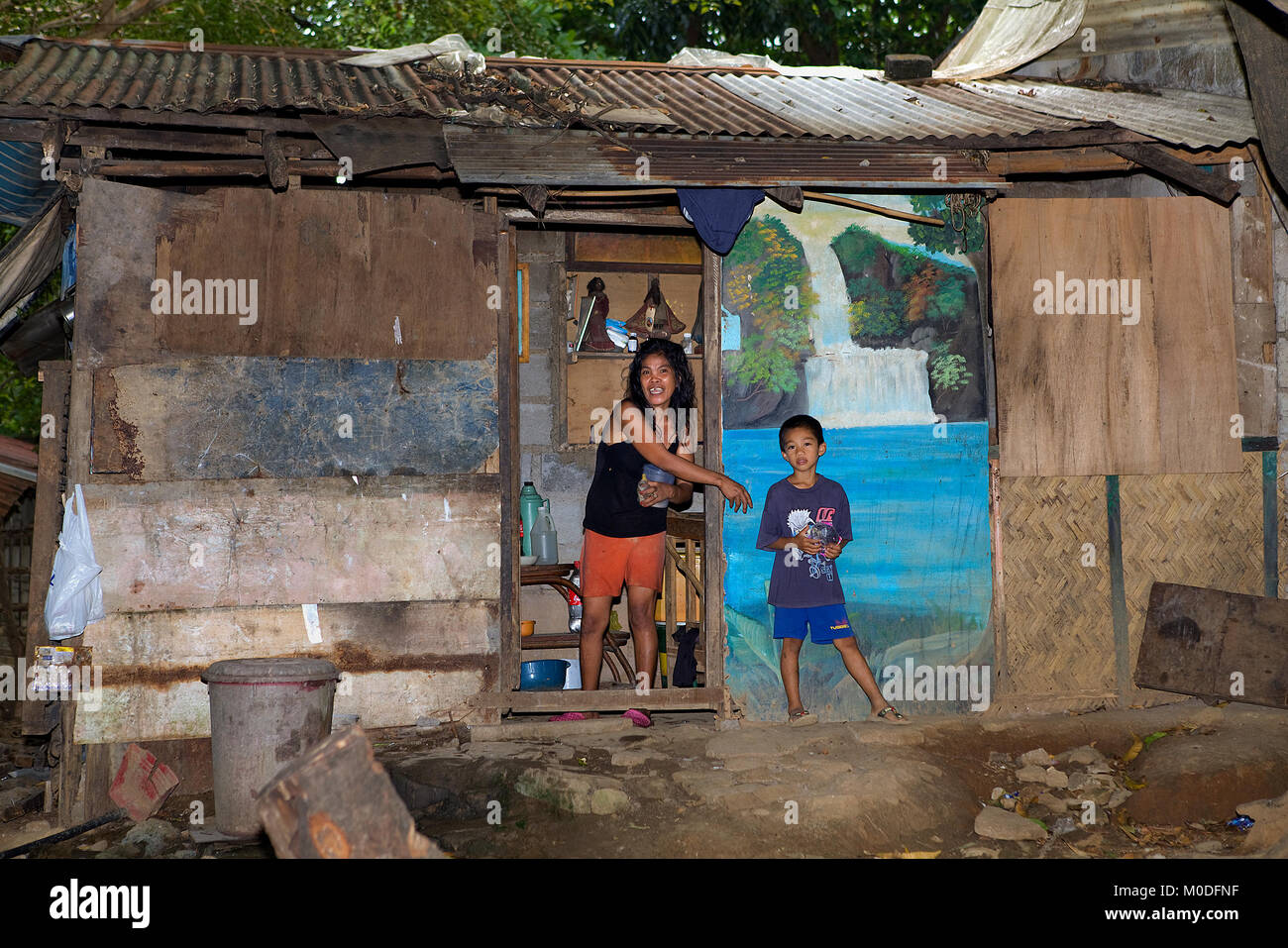Una mujer filipina y su hijo tienen un duro, pero feliz de la vida en su casa de chabolas hechas de encontrados y los restos de materiales. Foto de stock