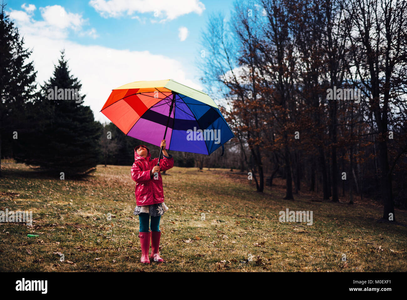 Chica de pie afuera sosteniendo un paraguas abierto Foto de stock