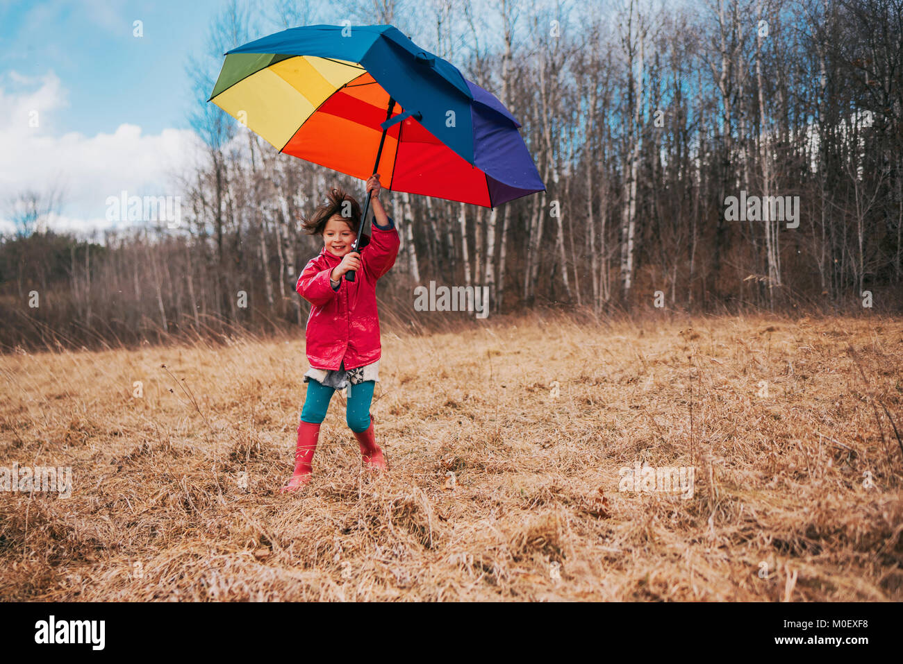 Chica sujetando un paraguas abierto en un día ventoso Foto de stock