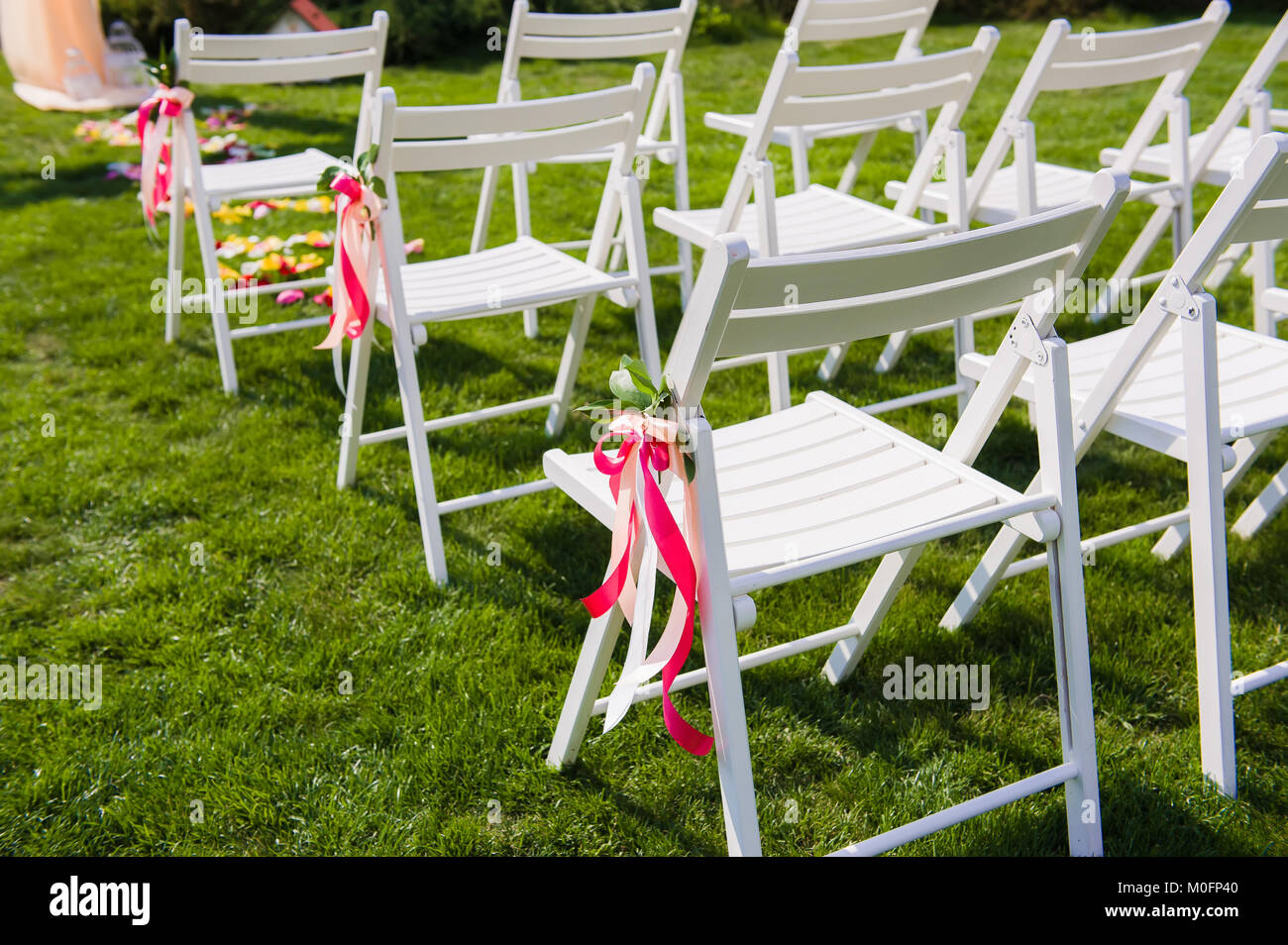Sillas blancas para invitados de boda. Detalle de la decoración para el  matrimonio con largas franjas brillantes atados a los asientos al aire  libre Fotografía de stock - Alamy