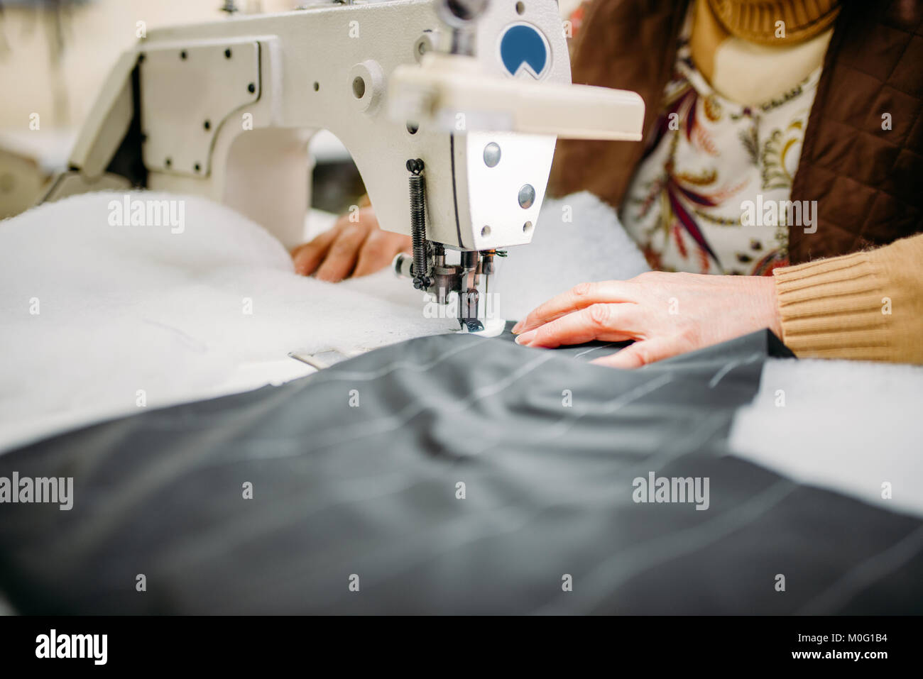 Costurera cose tejidos en una máquina de coser. La sastrería o la costura  en la fábrica de ropa, costura Fotografía de stock - Alamy